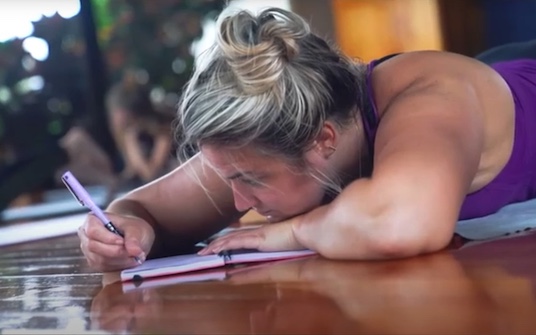 Woman journaling on yoga studio floor